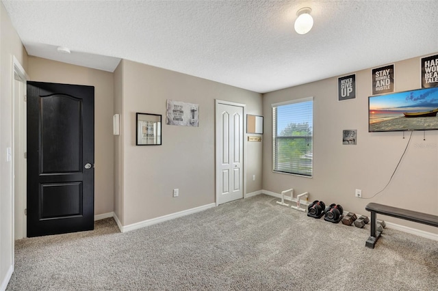 workout area with light carpet and a textured ceiling