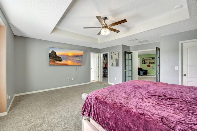 carpeted bedroom featuring ceiling fan, a raised ceiling, and a textured ceiling