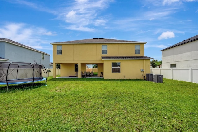 rear view of property featuring a yard, a patio, a trampoline, and central AC