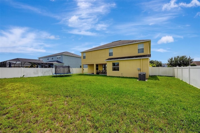 10820 Carloway Hills Dr, Wimauma, FL 33598 - rear view of property with central AC unit, a yard, a fenced backyard, stucco siding, and a trampoline