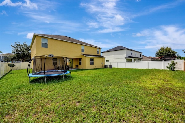 rear view of property with a yard and a trampoline