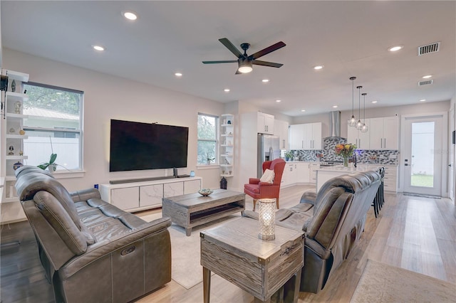 living room with plenty of natural light, light hardwood / wood-style flooring, and ceiling fan