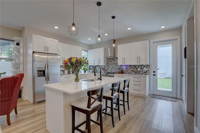 2860 14th Ave N, Saint Petersburg, FL 33713 - kitchen featuring light countertops, wall chimney exhaust hood, a sink, light wood-style floors, and stainless steel fridge with ice dispenser