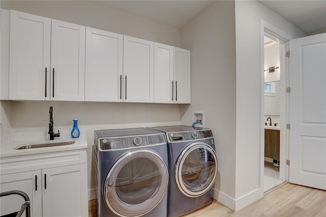 2860 14th Ave N, Saint Petersburg, FL 33713 - laundry area with washer and clothes dryer, baseboards, a sink, light wood-style floors, and cabinet space