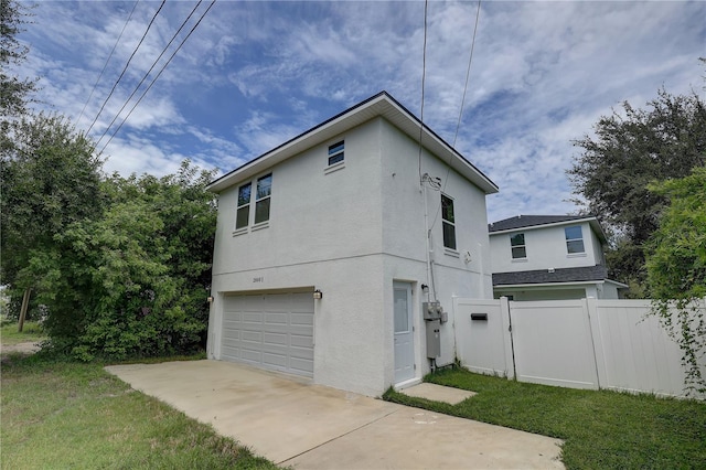 2860 14th Ave N, Saint Petersburg, FL 33713 - view of side of home featuring concrete driveway, stucco siding, fence, an attached garage, and a yard