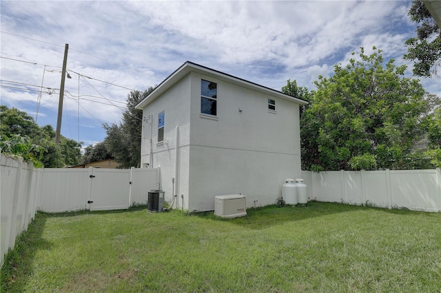 rear view of house featuring a lawn and central air condition unit