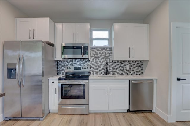 2860 14th Ave N, Saint Petersburg, FL 33713 - kitchen featuring light countertops, light wood-style flooring, appliances with stainless steel finishes, white cabinetry, and a sink
