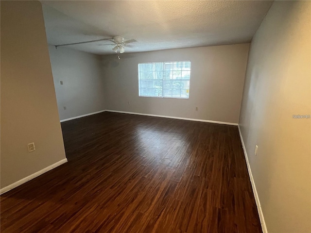 unfurnished room with a textured ceiling, dark wood-type flooring, and ceiling fan