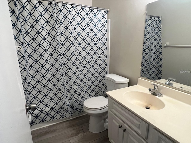 bathroom featuring toilet, a shower with shower curtain, vanity, and wood finished floors
