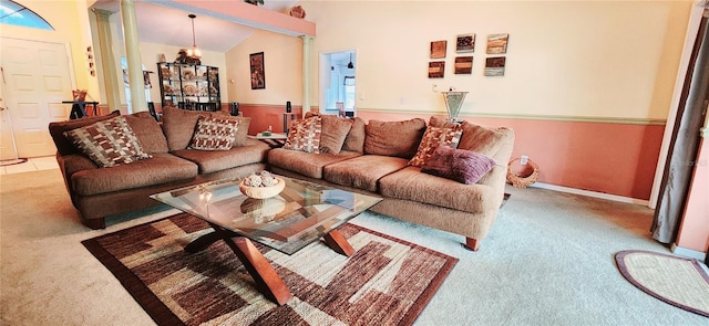 carpeted living area with baseboards, vaulted ceiling, and ornate columns