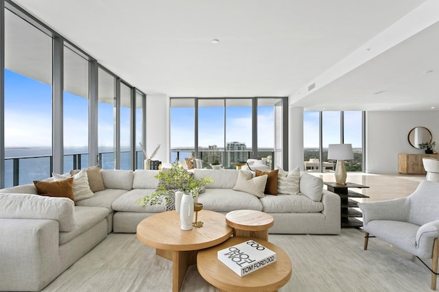 living room with a water view, a wall of windows, and light hardwood / wood-style floors