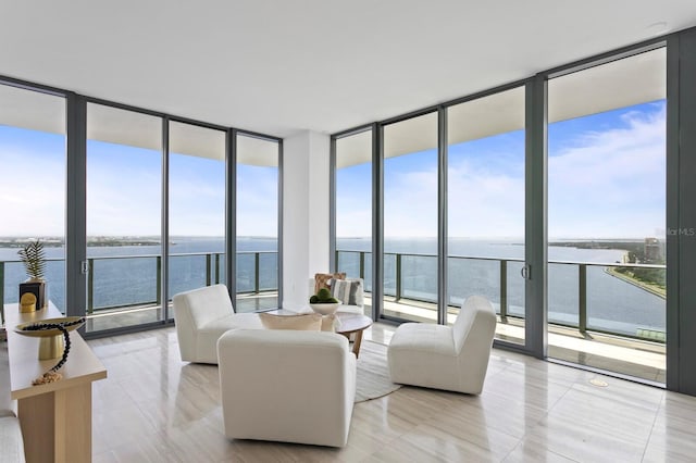 tiled living room with a wealth of natural light, a water view, and a wall of windows