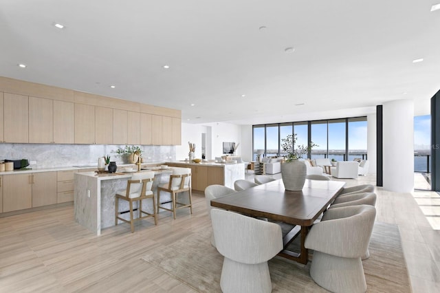 dining room with floor to ceiling windows, light wood-type flooring, and a water view