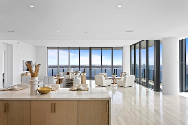 kitchen featuring a water view, light stone counters, and a wall of windows