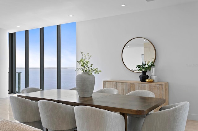 dining room featuring a water view, expansive windows, and light wood-type flooring