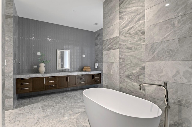 bathroom with tile walls, a tub to relax in, and vanity