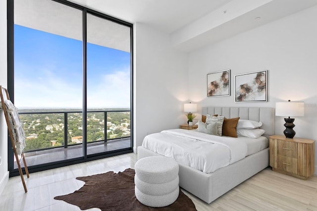 bedroom featuring floor to ceiling windows, access to outside, and light hardwood / wood-style floors