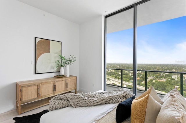 bedroom featuring a wall of windows and hardwood / wood-style flooring