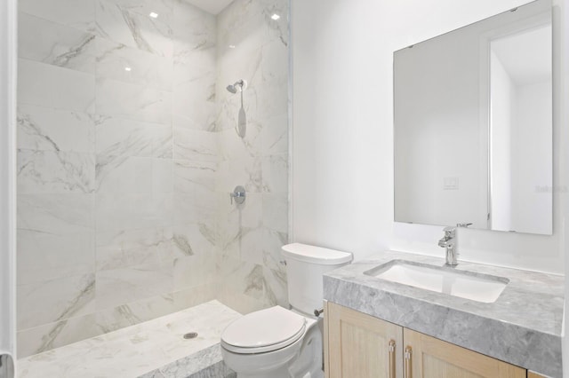 bathroom with tiled shower, toilet, and vanity