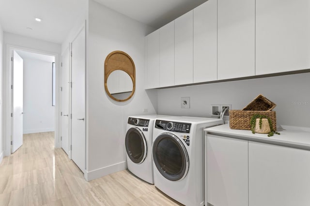 washroom featuring light hardwood / wood-style flooring, cabinets, and washing machine and clothes dryer