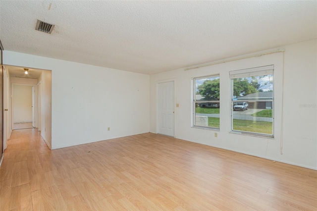 unfurnished room featuring a textured ceiling and light hardwood / wood-style floors