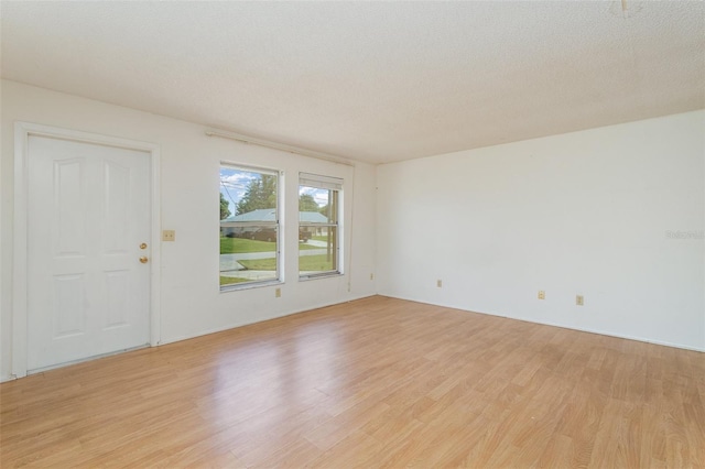 unfurnished room featuring a textured ceiling and light hardwood / wood-style flooring