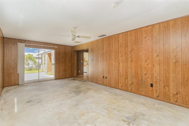 spare room featuring wooden walls and ceiling fan