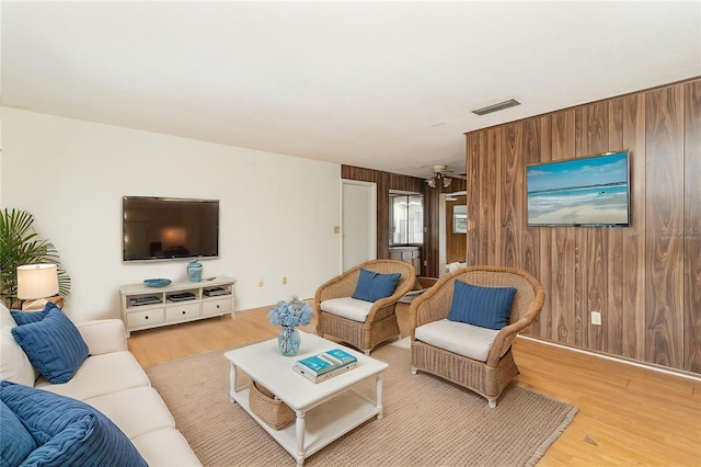 living room with light hardwood / wood-style flooring and wood walls