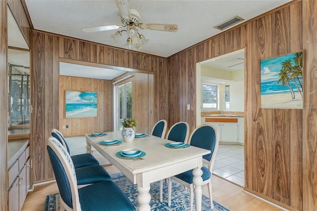 dining area featuring sink, a wealth of natural light, wooden walls, and ceiling fan