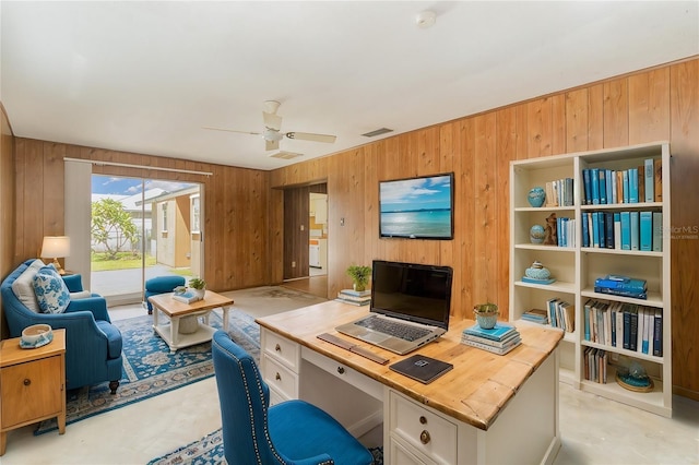 office area with ceiling fan and wooden walls