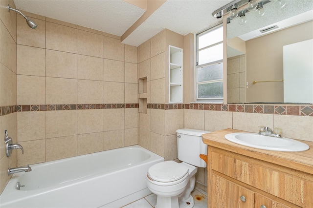 full bathroom featuring tile patterned floors, tiled shower / bath, toilet, a textured ceiling, and tile walls