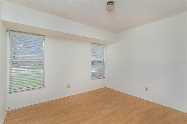 unfurnished room featuring a textured ceiling and light wood-type flooring