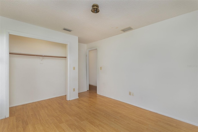 unfurnished bedroom with a textured ceiling, light hardwood / wood-style flooring, and a closet