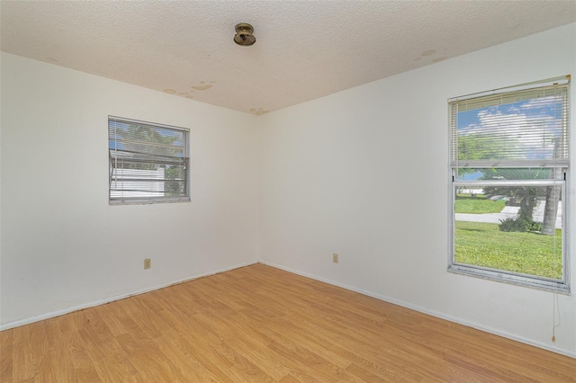 spare room with a textured ceiling and light wood-type flooring