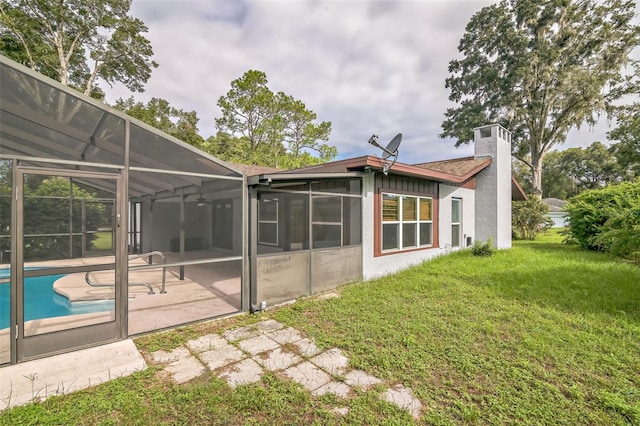 back of house with a lawn, glass enclosure, and a patio area