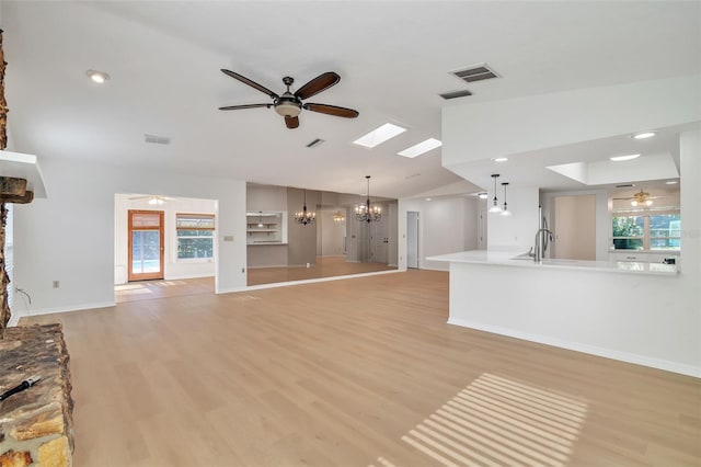 unfurnished living room featuring a notable chandelier, a wealth of natural light, vaulted ceiling, and light hardwood / wood-style floors