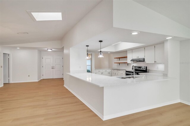 kitchen featuring white cabinets, light wood-type flooring, hanging light fixtures, and kitchen peninsula