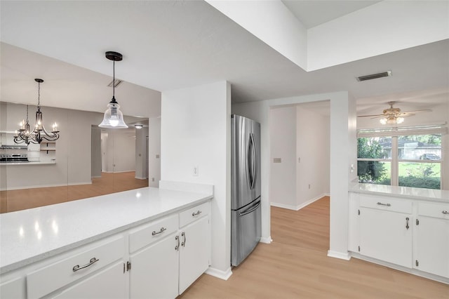 kitchen featuring white cabinets, stainless steel refrigerator, light hardwood / wood-style flooring, an inviting chandelier, and decorative light fixtures