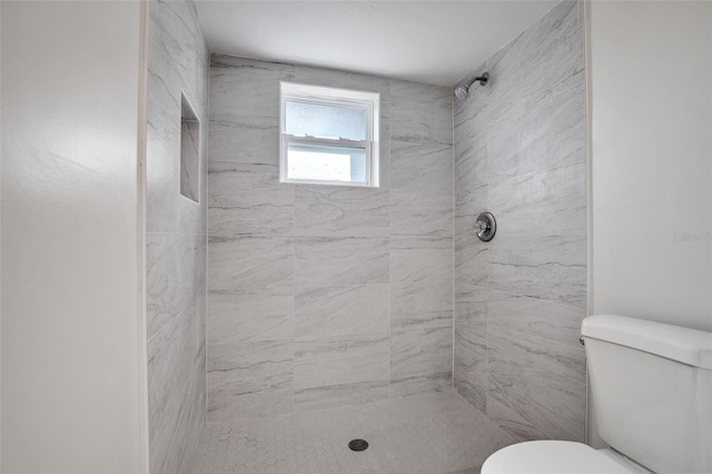 bathroom featuring tiled shower and toilet