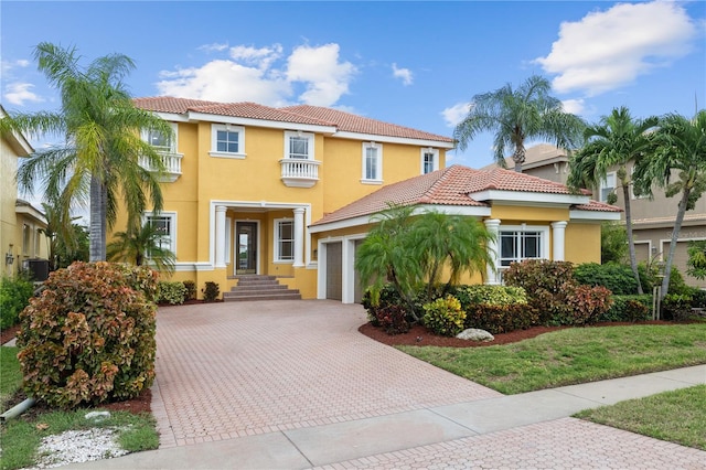 mediterranean / spanish-style home featuring a garage, central AC, and a front yard