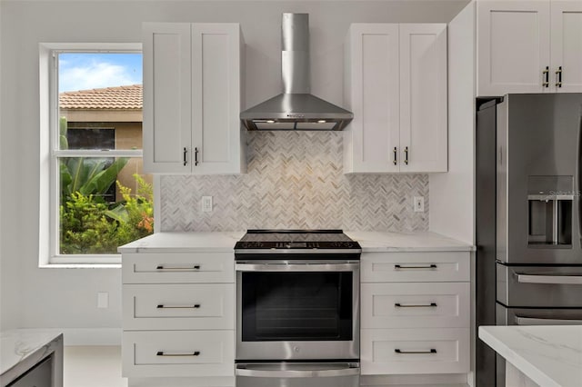 kitchen featuring stainless steel appliances, wall chimney exhaust hood, white cabinets, and light stone counters