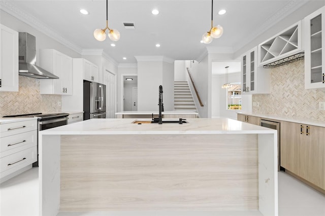 kitchen with pendant lighting, stainless steel appliances, sink, and wall chimney range hood