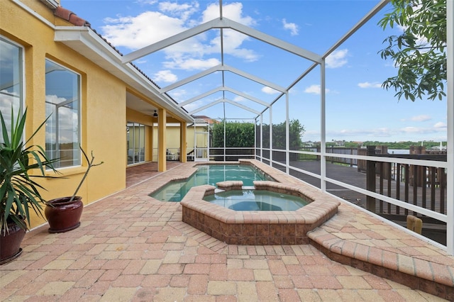 view of pool featuring glass enclosure, a patio, and an in ground hot tub