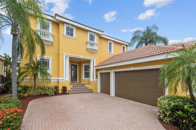 mediterranean / spanish-style house featuring a garage, decorative driveway, and stucco siding