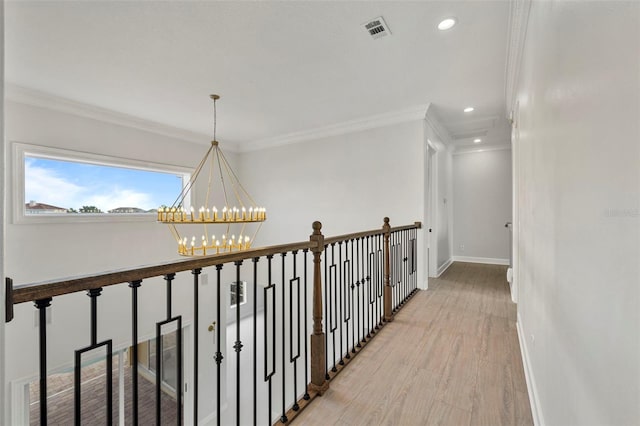 hallway featuring baseboards, visible vents, an inviting chandelier, crown molding, and light wood-style floors