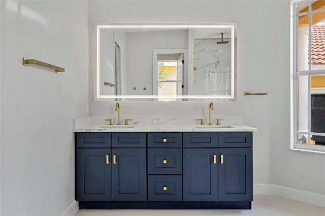 bathroom with a marble finish shower, double vanity, and baseboards
