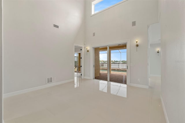 tiled entrance foyer featuring a towering ceiling and baseboards