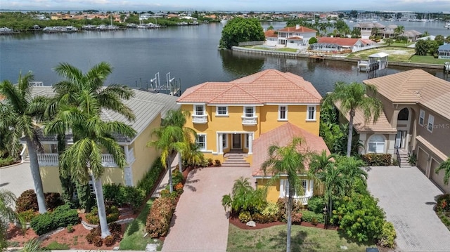 view of front of house with stucco siding, a water view, decorative driveway, a tile roof, and a balcony