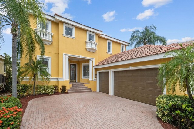 1233 Acappella Ln, Apollo Beach, FL 33572 - mediterranean / spanish-style home featuring stucco siding, decorative driveway, a balcony, and an attached garage