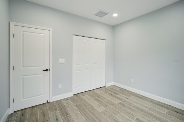 unfurnished bedroom with baseboards, visible vents, light wood-style floors, a closet, and recessed lighting